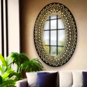 Oval Lippan art wall mirror with an intricate gold-and-black geometric design, displayed in a modern living room with green plants